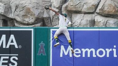 Denzel Clarke, jardinero de los Atléticos, realiza espectacular atrapada al saltar sobre la barda para un out magistral